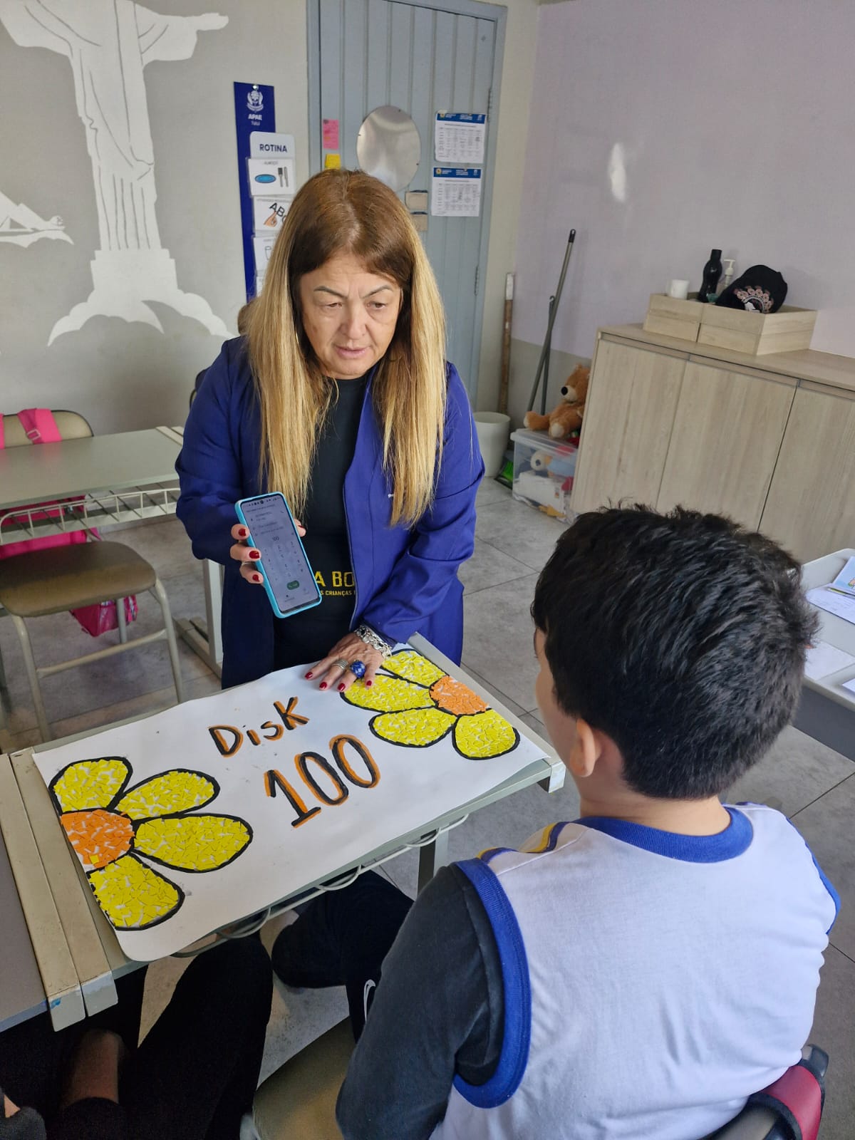 Professora em atividade sobre Disk 100