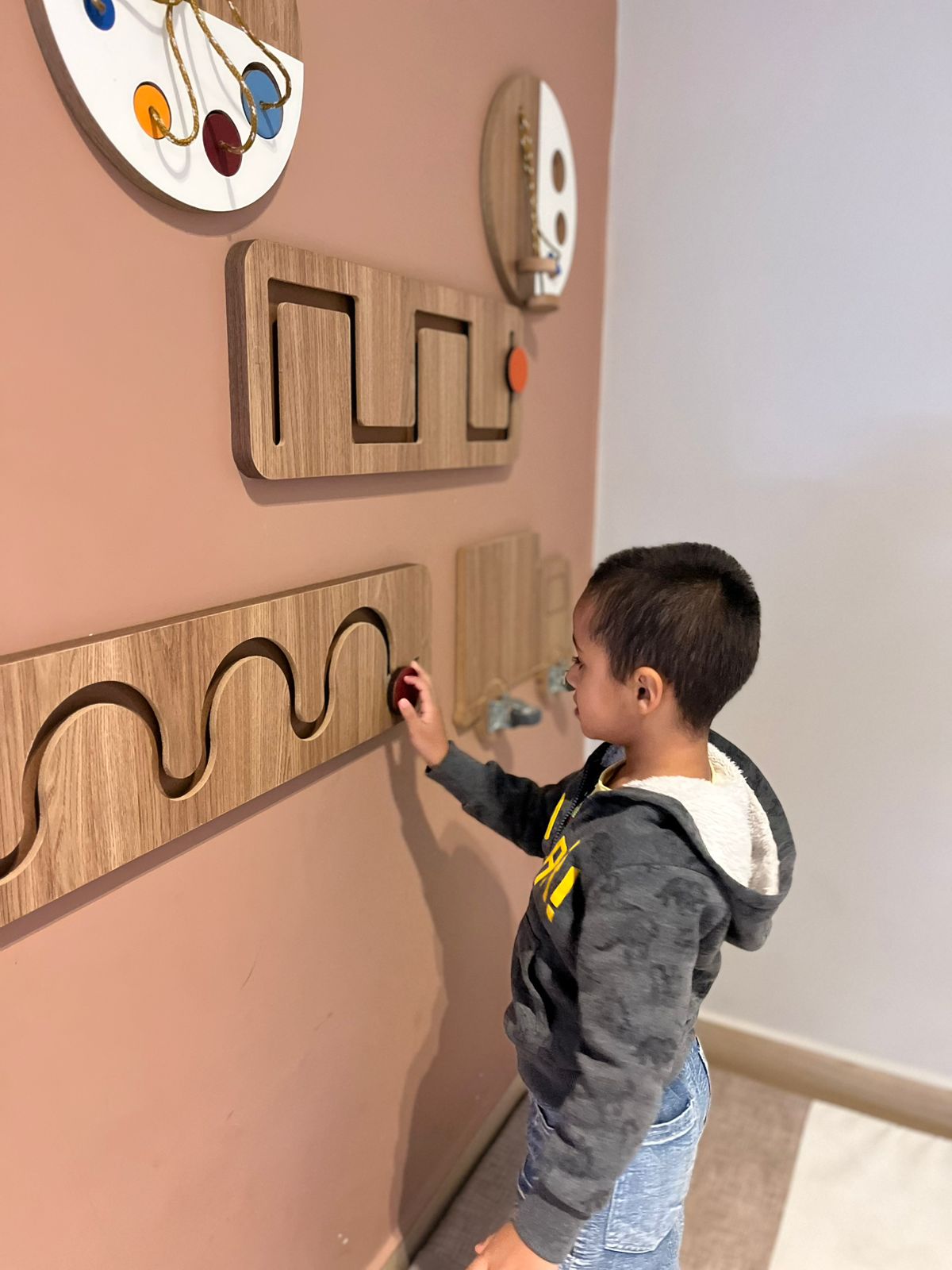 Criança em estimulação sensorial com painel de madeira
